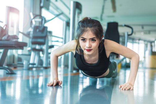 Asian woman fitness girl do pushing ups at fitness gym. Healthcare and Healthy concept. Training and Body build up theme. Strength and Beauty concept