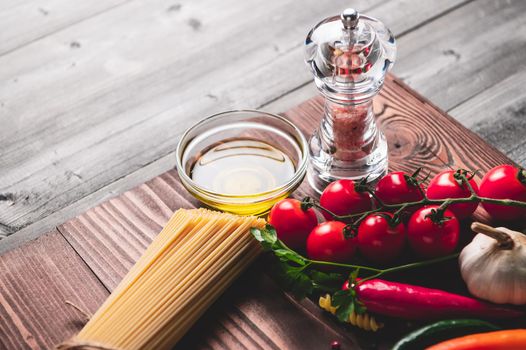 Tasty appetizing italian spaghetti pasta ingredients for kitchen cuisine with tomato, cheese parmesan, olive oil, fettuccine and basil on wooden brown table. Food Italian recipe homemade. Top view