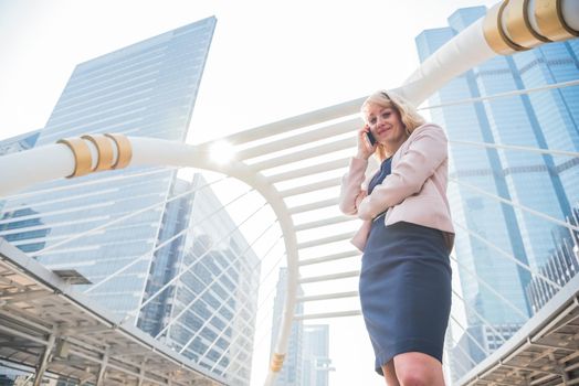 Beauty businesswoman using mobile phone for communicating with customers in the city. Business and Technology concept.  Metropolis theme.