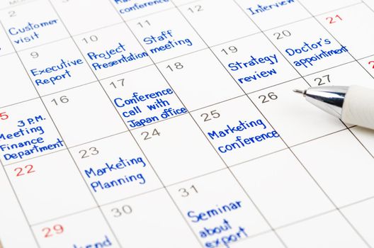 Handwriting scheduling appointments on calendar sheet with pen.