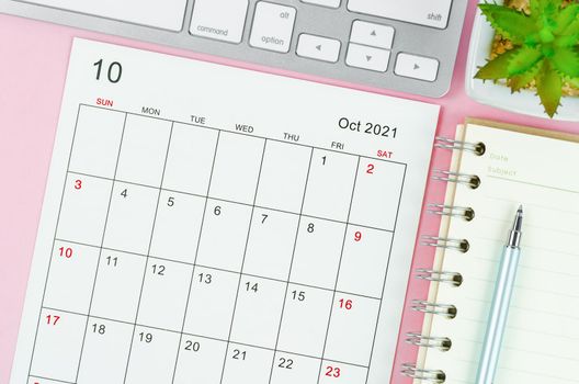 October 2021 calendar sheet with keyboard computer on pink background.