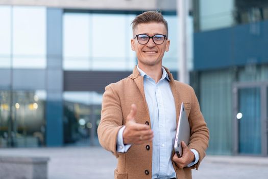 Business. Businessman Giving Hand For Handshake Welcome Gesture Adult Caucasian Male Business Person Holding Closed Laptop Give Hand Ready Handshake Office Building Background