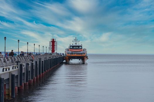 The catamaran passenger ferry is moored to the sea pier. Comfortable sea passenger transport