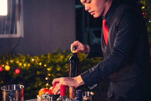 Professional bartender preparing fresh lime lemonade cocktail in drinking wine glass with ice at night bar clubbing counter. Occupation and people lifestyles concept. Outdoor background