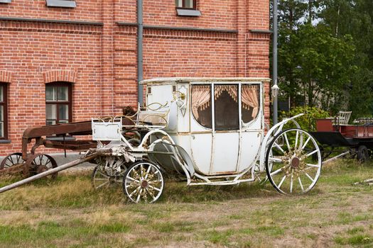 Old white carriage on the background of a red brick building. White vintage carriage