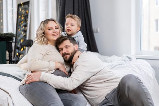 Happy family concept Mother father and little son have fun at home Caucasian family indoors Pregnant mom beard dad and funny little boy