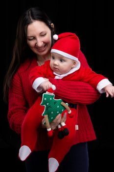 Mom and little child at Christmas. A woman holds her son in her arms, who is dressed in Santa Claus clothes.