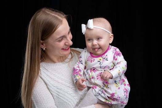 Mom holds a little happy daughter in her arms. Motherhood.