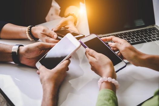 Group of young hipsters holding phone in hands at office. Friends having fun together with smartphones. Technology and communication concept. Black screen. Side view of teenager team using  phones