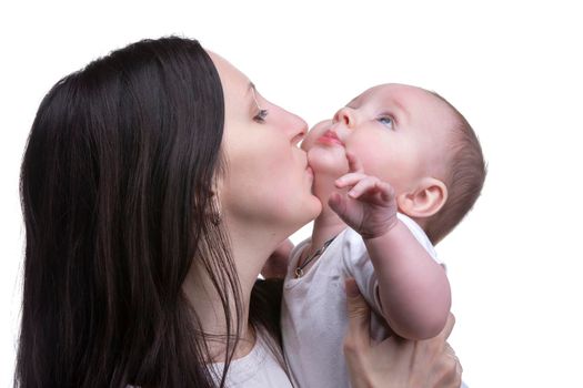 Mom kisses her little son on a light background. Motherhood.