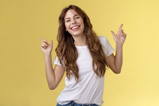Outgoing cheerful attractive woman curly haircut wear casual white t-shirt dancing party having fun pointing up disco moves having fun smiling broadly enjoy holidays anticipating summer trip. Lifestyle.