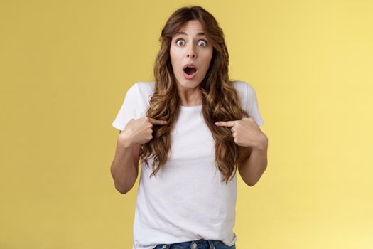 Shocked impressed speechless surprised girl gasping drop jaw pointing herself chest stare camera astonished unexpected promotion being chosen picked winning lottery stand yellow background.