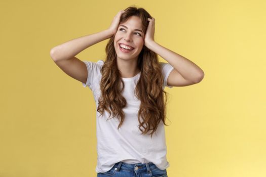 Carefree happy attractive smiling girl hold head curly hairstyle turn away upper left corner sunny summer day excellent lucky weekends standing amused excited adventures start yellow background. Lifestyle.