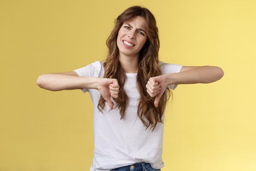 Very bad give up please. Displeased unimpressed judgemental curly-haired attractive girl tilt head cringe grimacing squinting disappointed show thumbs down disagree negative awful opinion.