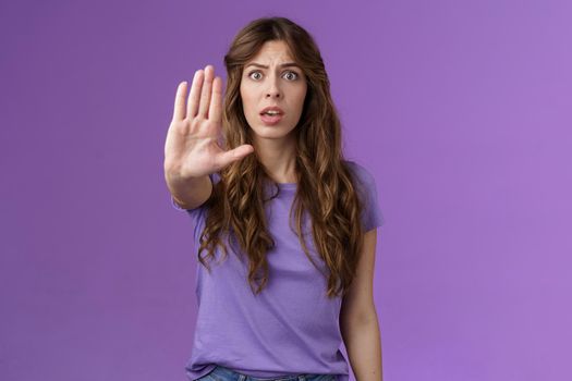 Worried shocked curly-haired woman gasping stare camera anxiously pull hand stop sign begging end prohibiting friend drive after drinking stand purple background forbid warn you purple background. Lifestyle.