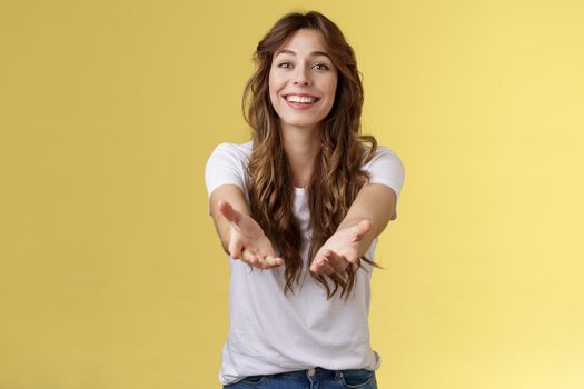Let me hold it. Sincere tender touched charming curly-haired girl reaching you extend arms smiling lovely tempting grab precious thing receive gift stand yellow background grateful cheerful.
