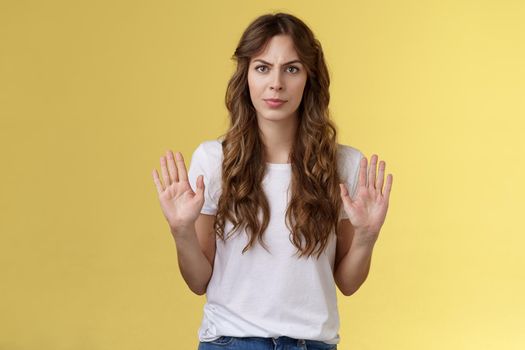 No thats enough. Serious-looking confident woman restrain man demand stay away give refusal look intense prohibit rejecting suspicious unpleasant offer stand yellow background. Copy space
