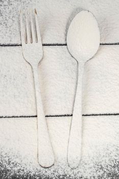 A fork and spoon on a cutting board are sprinkled with flour.Cutlery on the board.