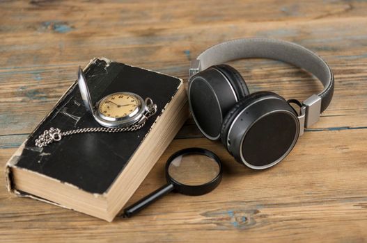 Black headphones and close book are on the wooden table. Audio book concept. Distance learning