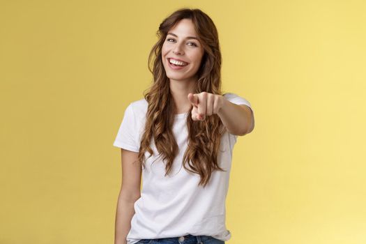 Hey you congrats. Joyful good-looking friendly enthusiastic lovely girl laughing happily pointing camera joking picking making choice congratulate excellent job stand yellow background smiling.