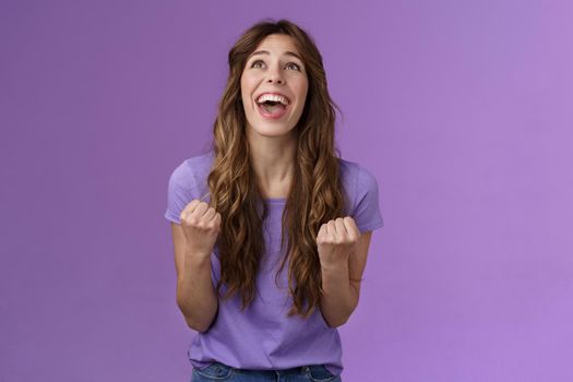 Relieved happy girl thank god awesome achievement celebrate success implore lord grateful fist pump yelling raise head up sky triumphing good news stand purple background joyful positive reaction. Lifestyle.