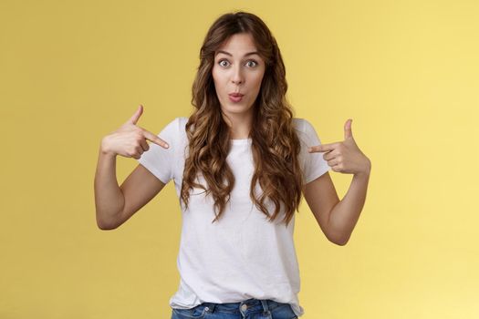 Wow just look. Impressed surprised cute wondered european girl pointing fingers center copy space white t-shirt folding lips amused astonished awesome promo great chance gaze you camera.