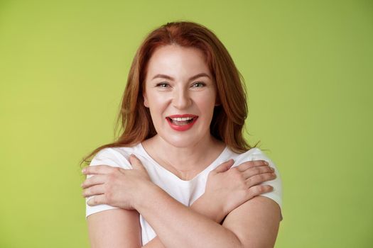 Cheerful charismatic happy good-looking redhead woman red lipstick cross hands chest smiling motivated excited having fun playful thrilled mood grinning enthusiastic standing green background.