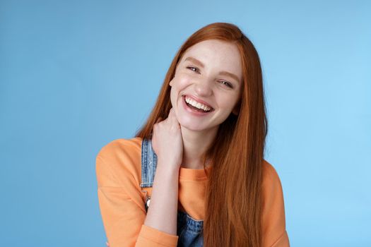 Lifestyle. Carefree silly flirty young redhead girlfriend having fun enjoying lovely date summer evening laughing out loud smiling broadly tilting head touching neck shy blushing acting cute blue background.