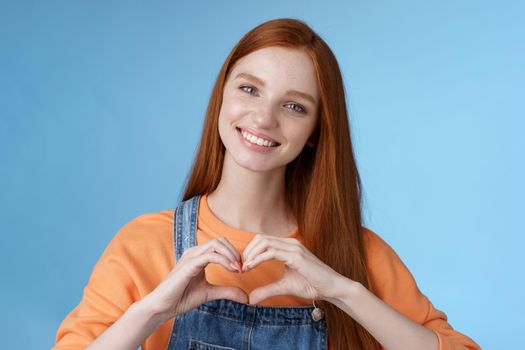 Love you. Attractive romantic tender redhead smiling gentle girlfriend blue eyes freckles show heart chest express sympathy romantic positive attitude confess passionate deep feelings, grinning cute.