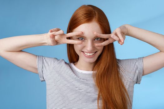 Sassy rebellious sensual good-looking redhead girl blue eyes smiling cheeky show peace victory signs eye grinning satisfied confident express self-assured positive attitude, studio background.
