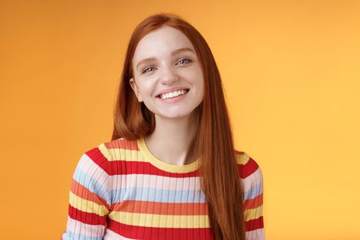 Friendly feminine pretty redhead caucasian female sibling smiling broadly have perfect happy mood talking casually enjoy fine summer sunny day standing orange background delighted relaxed.