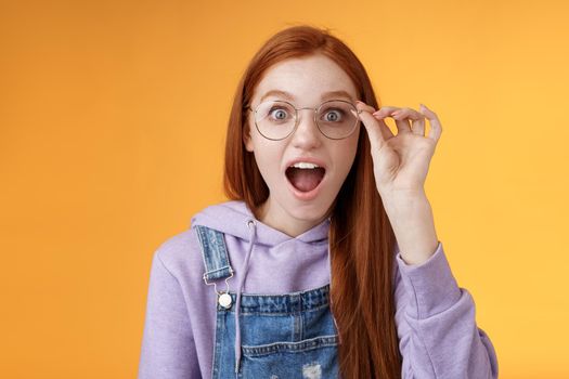 Omg so cool. Portrait amazed speechless excited redhead girl drop jaw amused stare camera surprised find out awesome product net touch glasses reading impressive post, orange background.
