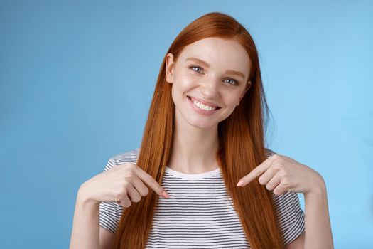 Visit place you love it. Friendly-looking kind gentle attractive redhead woman showing advertisement copy space pointing index fingers down tilting head smiling helpful recommend promo.