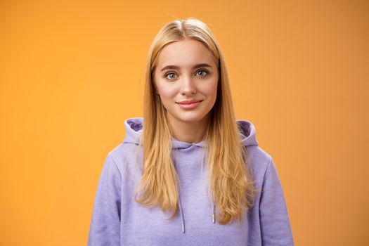 Waist-up delicate tender friendly-looking blond european girl in hoodie smiling supportive talking listening friends story nice interesting conversation standing casually orange background.