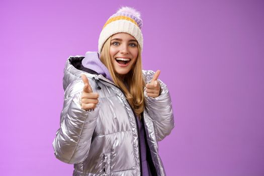 What up hey friend. Friendly energized happy smiling cute blond girl checking out cool girlfriend outfit nice choice pointing finger pistols camera standing amused grinning in winter jacket.