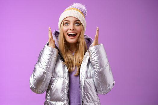 Impressed fascinated speechless attractive blond girl explaining awesome situation shaking hands excited smiling gasping happily widen eyes surprised, standing purple background amused.