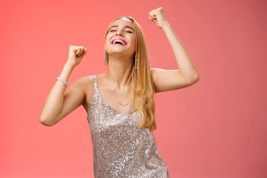 Excited carefree happy stylish blond european woman having fun dancing smiling broadly laughing happiness enjoying awesome music party rocking lighting dance-floor standing red background.