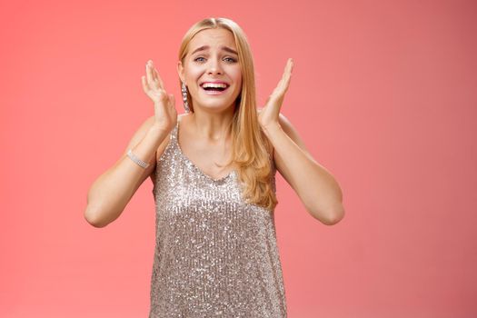 Lifestyle. Amazed freaked out excited blond female fan see favorite celebrity star screaming astonished happy look emotive wanna cry happiness waving palms near head thrilled red background.