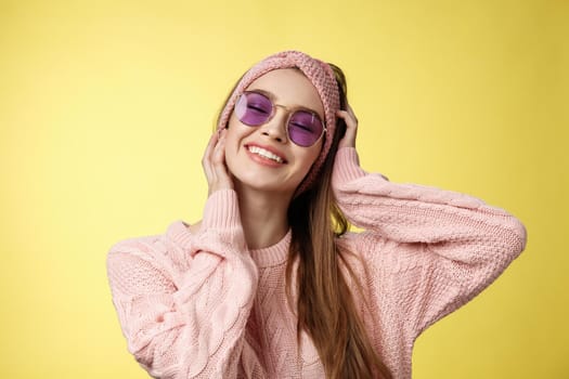 Waist-up shot of lovely glamour carefree young woman ready for vacation, packing bags move out of winter, travelling, smiling joyfully close eyes happily, touching face, wearing sunglasses sweater.