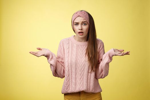 What big deal, why so fuss. Portrait of frustrated confused and clueless cute young pretty woman in knitted sweater, headband shrugging in dismay asking question unaware what happening.