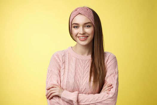 Waist-up shot of confident creative joyful cute european female model in knitted pink sweater, headband, cross arms self-assured, satisfied, smiling pleased and motivated, looking delighted.