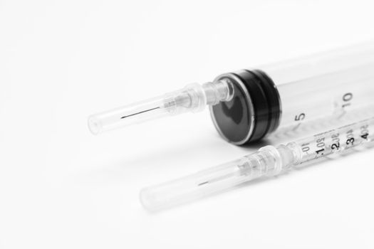 Two medical syringes for vaccine injection on white background. Close-up of large and small syringe. Selective focus.