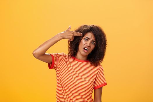 I would rather kill myself. Displeased bored and dissatisfied attractive bothered girlfriend in striped t-shirt tilting head, grimacing from dislike putting finger gun to forehead, commiting suicide. Copy space