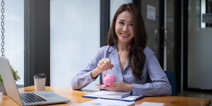 Young woman smiling putting a coin inside piggy bank as savings for investment. wealth and financial concept
