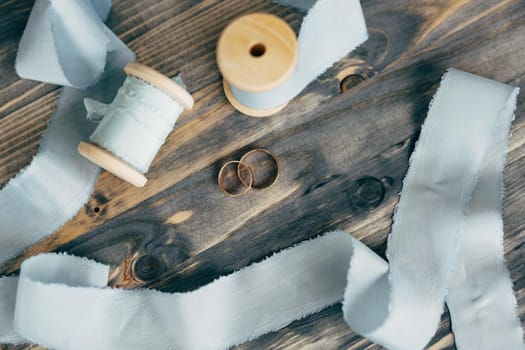 Top view of wedding gold rings on a wooden surface with gray ribbon spools. High quality photo
