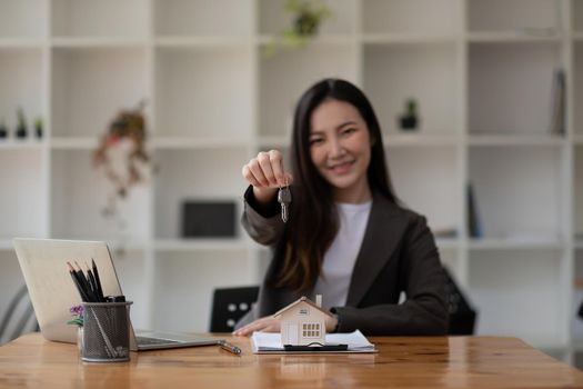 Real estate agent hand holding house model and keys.