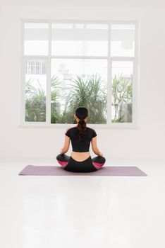 A woman practices yoga near the window