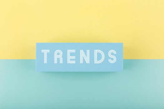 Trends written on rectangle in the middle of multicolored light blue and yellow background. Minimal concept of newest, latest, hot and popular trends of any industry
