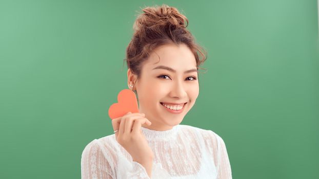 Beautiful asian girl with a heart, Valentine's Day, isolated on green background