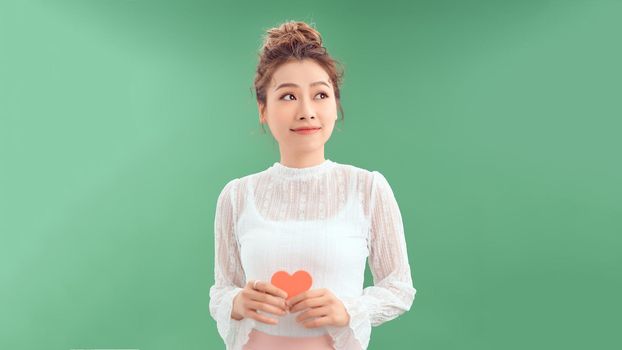 woman holding heart paper valentites card in green background